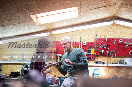 Father explaining tool to son in auto repair shop