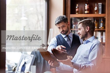 Businessmen examining dress shoes in menswear shop