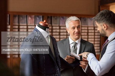 Tailor explaining suit to businessman in menswear shop