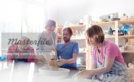 Mature adults using pottery wheels in studio