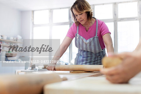 Woman rolling clay with rolling pin in studio