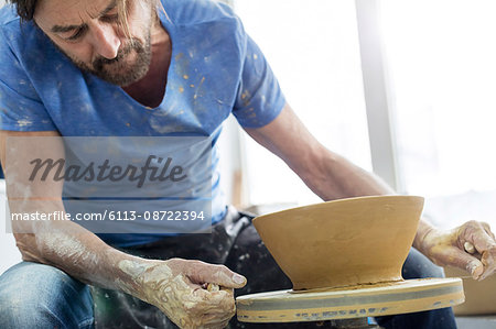 Mature man using pottery wheel in studio