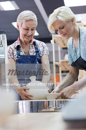 Women placing pottery in kiln in studio