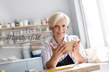 Portrait smiling mature woman holding bowl in pottery studio