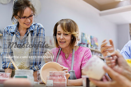 Mature woman painting pottery in studio