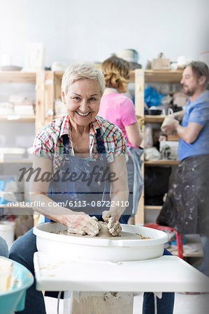 Portrait smiling senior woman using pottery wheel in studio