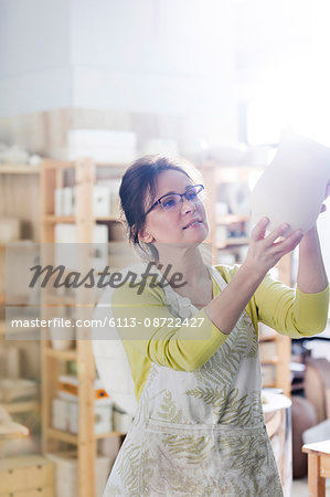 Mature woman examining pottery vase in studio