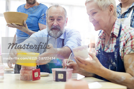 Senior couple painting pottery in studio