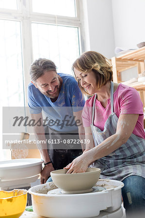 Mature couple using pottery wheel in studio