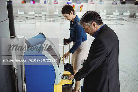 Business people using self service check-in machine at airport