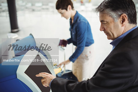 Businessman using self service check-in machine at airport Businessman using self service check-in machine at airport