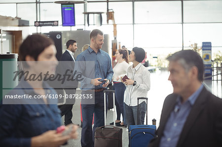 Business people holding boarding pass and using mobile phone in airport terminal