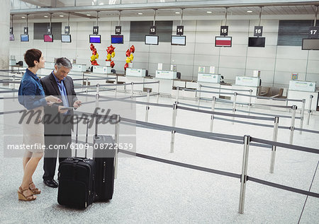 Business people waiting at check-in counter with luggage in airport terminal