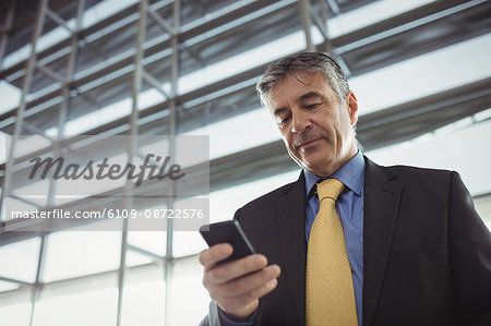 Businessman using mobile phone in waiting area at airport terminal