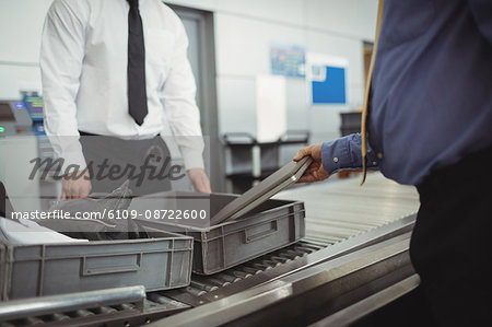 Man putting laptop into tray for security check at airport