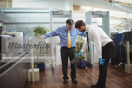 Airport security officer using a hand held metal detector to check a passenger in airport
