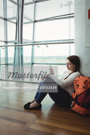 Woman listening to music on mobile phone while sitting in waiting area