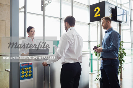 Man giving his passport to airline check-in attendant at airport check-in counter Man giving his passport to airline check-in attendant at airport check-in counter
