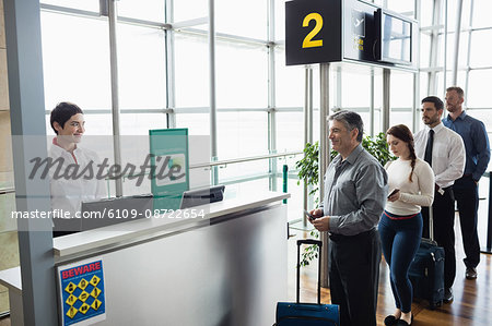Passengers waiting in queue at check-in counter in airport terminal