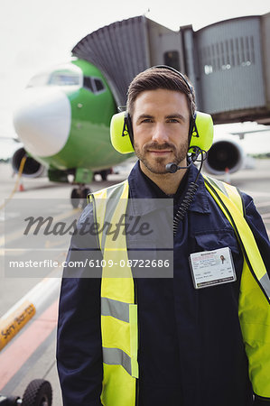 Portrait of airport ground crew standing on runway at airport terminal