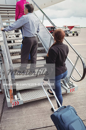 Passengers climbing on the stairs and entering into the airplane at airport