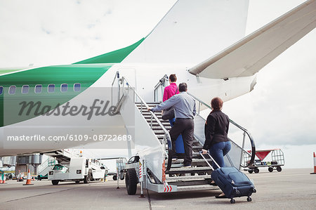 Passengers climbing on the stairs and entering into the airplane at airport