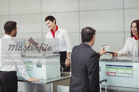 Airline check-in attendant handing passport to passenger at airport check-in counter
