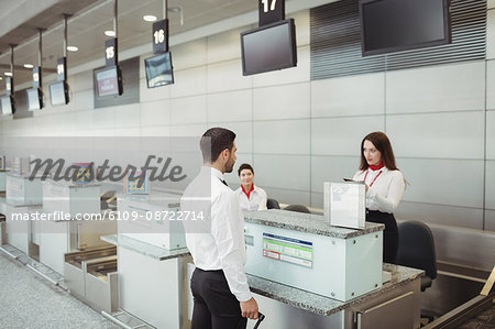 Airline check-in attendant checking passport of passenger at airport check-in counter