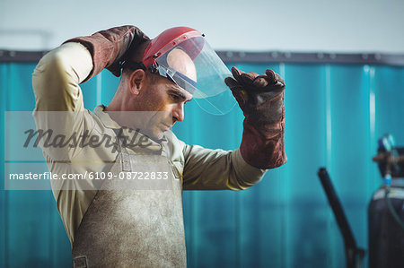 Male welder wearing protective helmet in workshop