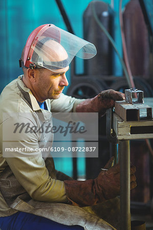 Male welder examining a piece of metal in workshop