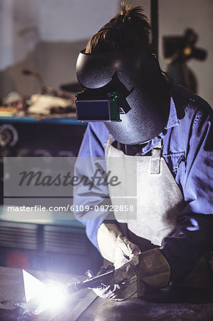 Female welder working on a piece of metal in workshop