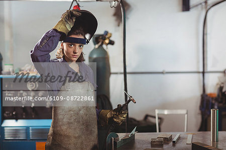 Male welder holding welding torch in workshop