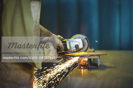 Mid-section of female welder using circular saw in workshop