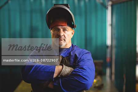 Portrait of male welder standing with arms crossed in workshop