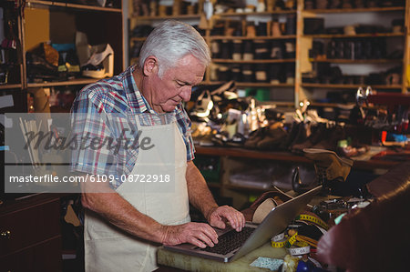 Shoemaker using laptop in workshop