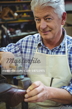 Portrait of shoemaker hammering on a shoe in workshop