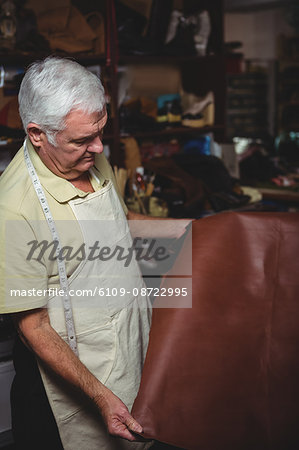 Shoemaker examining a piece of leather in workshop