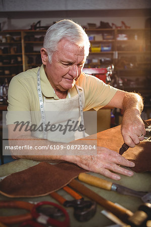 Shoemaker cutting a piece of leather in workshop