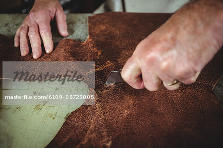 Shoemaker cutting a piece of leather in workshop