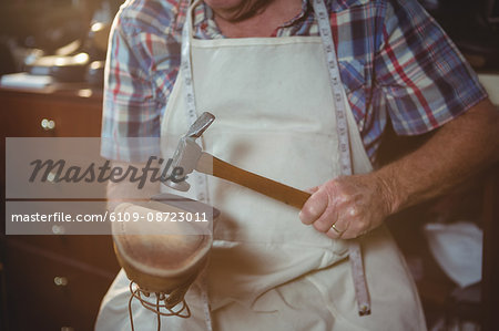 Shoemaker hammering on a shoe in workshop