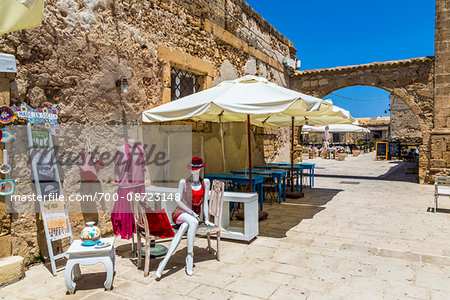 Outdoor store display of cloting and accessories along the cobblestone street in the village of Marzamemi in the Province of Syracuse in Sicily, Italy