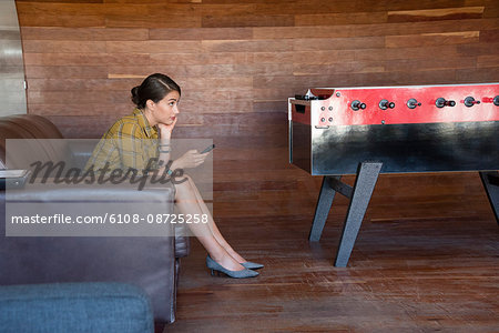 Businesswoman sitting on sofa using a mobile phone