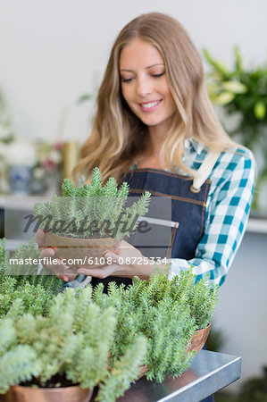 Happy female florist holding a potted plant