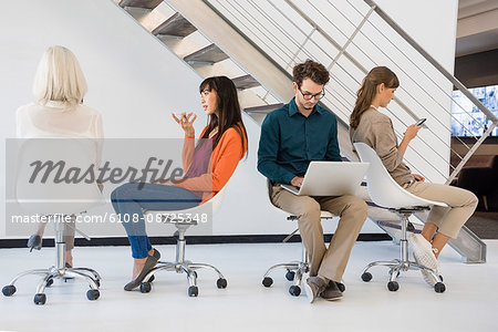 Business executives sitting on chairs busy in different activities