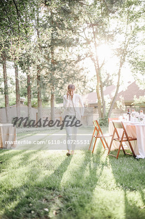 Woman standing in a sunlit garden, talking on her mobile phone.