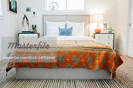 A bedroom in an apartment with a double bed and a retro look antique patterned patchworked bed cover.