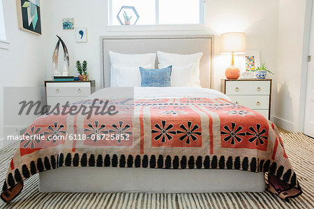 A bedroom in an apartment with a double bed and a retro look antique patterned patchworked bed cover.