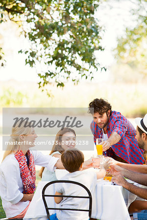 Friends clinking glasses while enjoying meal together outdoors