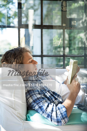 Young man reading book on couch