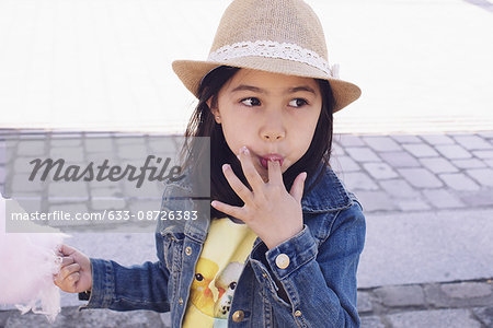 Girl eating cotton candy, licking fingers